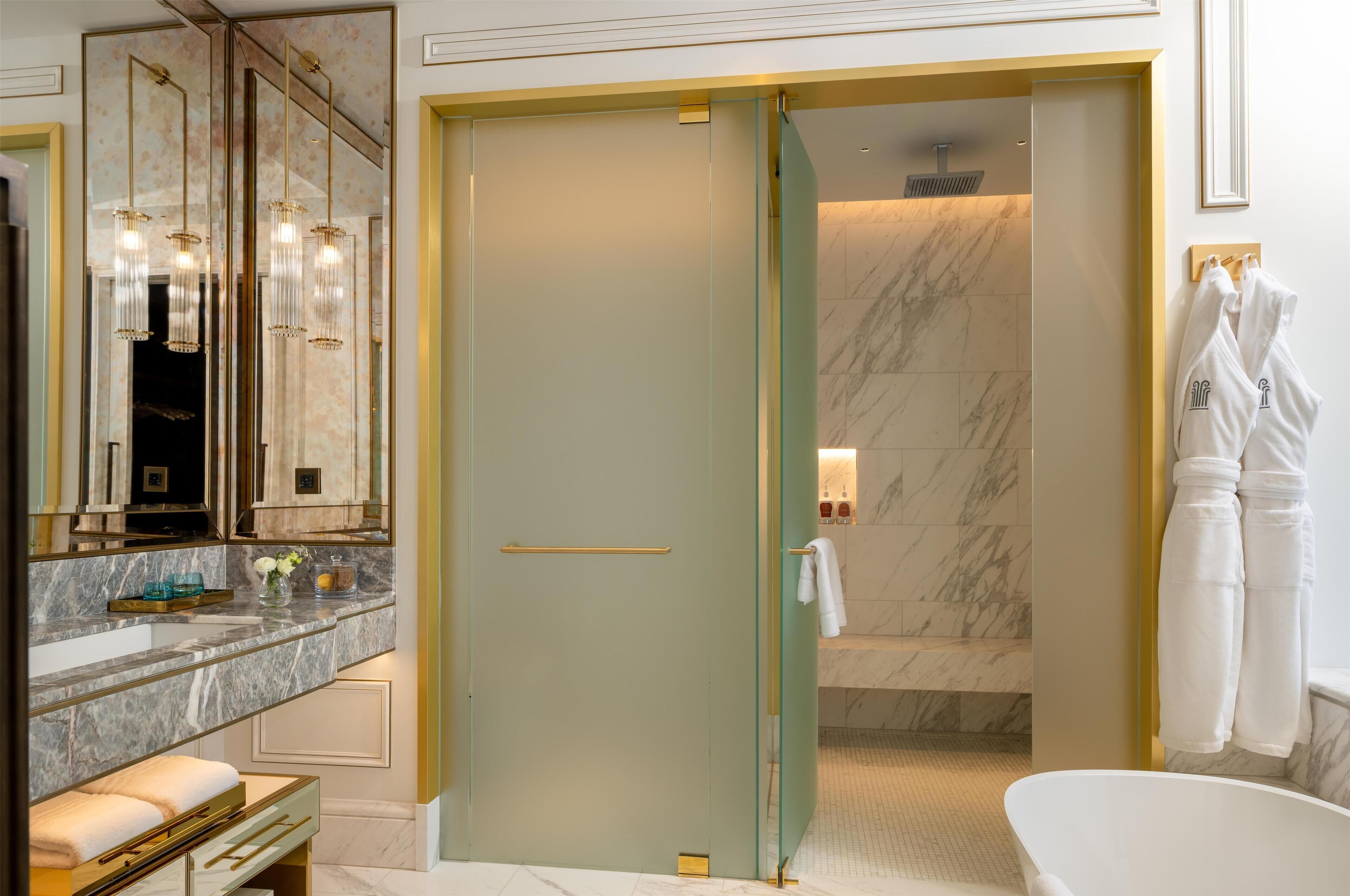 Une salle de bain moderne avec un grand miroir, une porte de douche en verre et une baignoire.