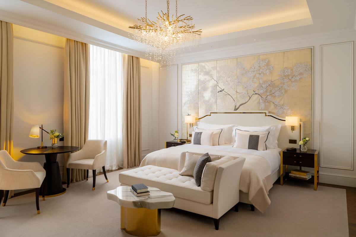 Une chambre spacieuse avec un grand lit, un coin salon avec une table et des chaises, et un élément décoratif mural.