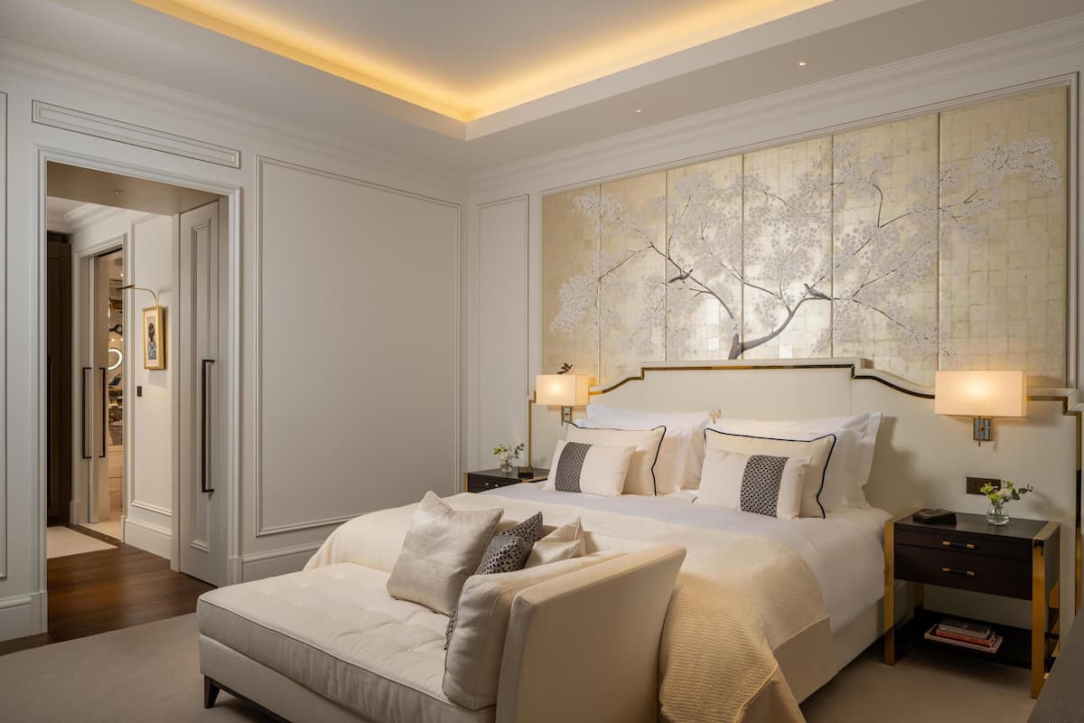 Une chambre spacieuse avec un grand lit, deux tables de chevet et une œuvre d’art accrochée au mur.