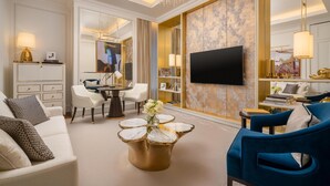 Un salón bien iluminado con televisión, asientos cómodos, una mesa de centro y un espejo decorativo.