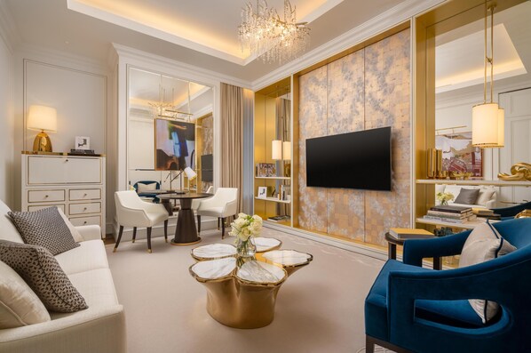 Un salon bien éclairé, équipé d’un téléviseur, de sièges confortables, d’une table basse et d’un miroir décoratif.