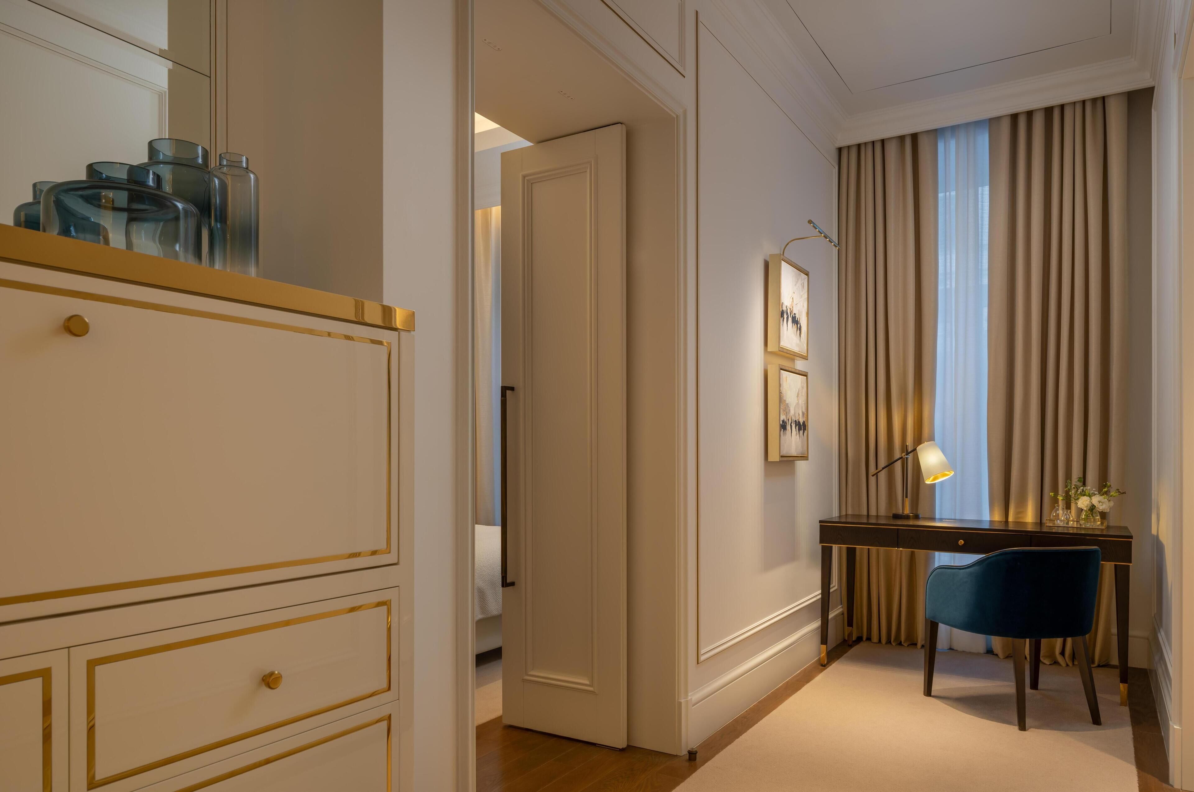 A hotel room with a desk, chair, and a large mirror.