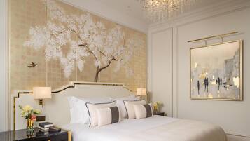 A hotel room with a large bed, two bedside tables, a wall-mounted artwork, and a chandelier.