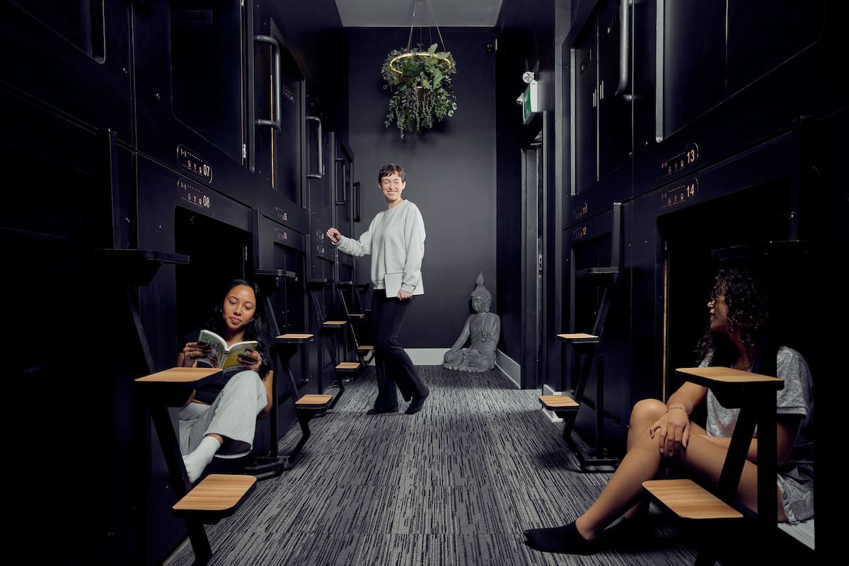 A modern hotel corridor with lockers, seating areas, and a Buddha statue.