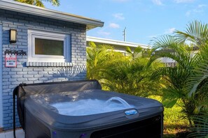 Un jacuzzi frente a una casa con un cartel que dice 'No se permite vidrio en la zona del jacuzzi'.