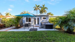 Una casa moderna con patio, mobiliario exterior y un jacuzzi.