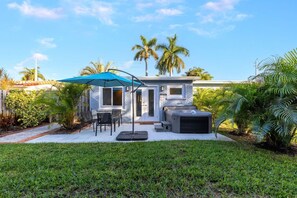 Una casa moderna con patio, mobiliario exterior y un jacuzzi.