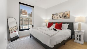 Un dormitorio moderno con una cama grande, una mesita de noche, un espejo y una ventana con vistas a la ciudad.