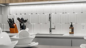 Una cocina moderna con azulejos blancos, un grifo de acero inoxidable y un dispensador de jabón en la encimera.