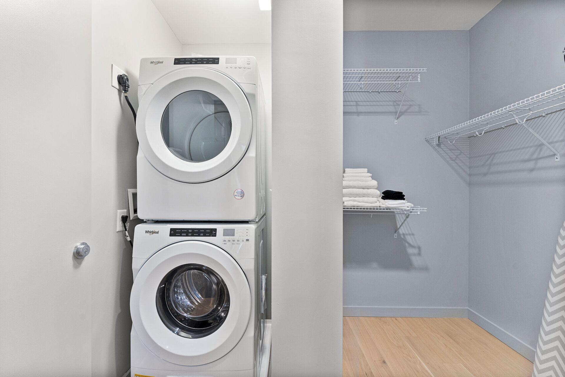 Una sala de bugaderia amb dues rentadores superposades i un estenedor de roba amb tovalloles pliegades.