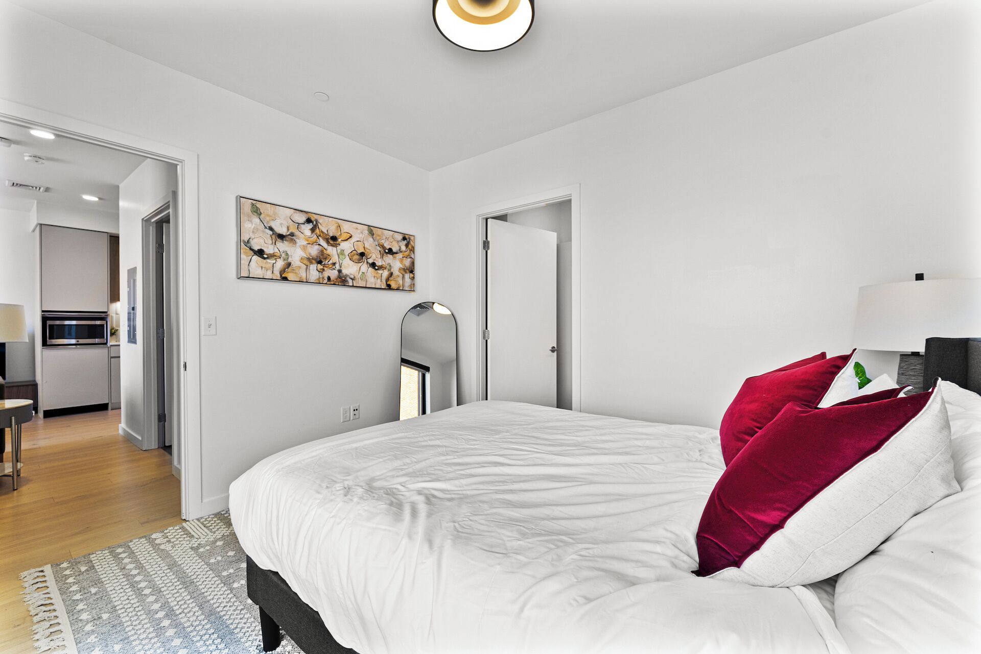 Un dormitorio moderno con una cama grande, un cuadro en la pared y vistas a la cocina.