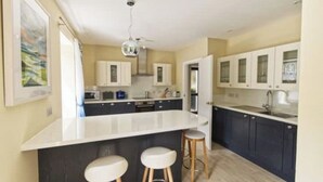 A modern kitchen with a large island, bar stools, and dark cabinetry. - Beautifully renovated property in heart of Tarbert (Tarbert)