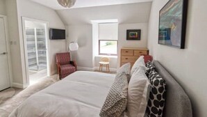 A bedroom with a large bed, a chair, a dresser, and a television on the wall. - Beautifully renovated property in heart of Tarbert (Tarbert)