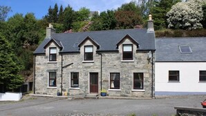 A stone house with a grey roof, multiple windows, and a paved front area. - Beautifully renovated property in heart of Tarbert (Tarbert)