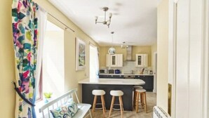 A kitchen with a central island, bar stools, and a window with curtains. - Beautifully renovated property in heart of Tarbert (Tarbert)