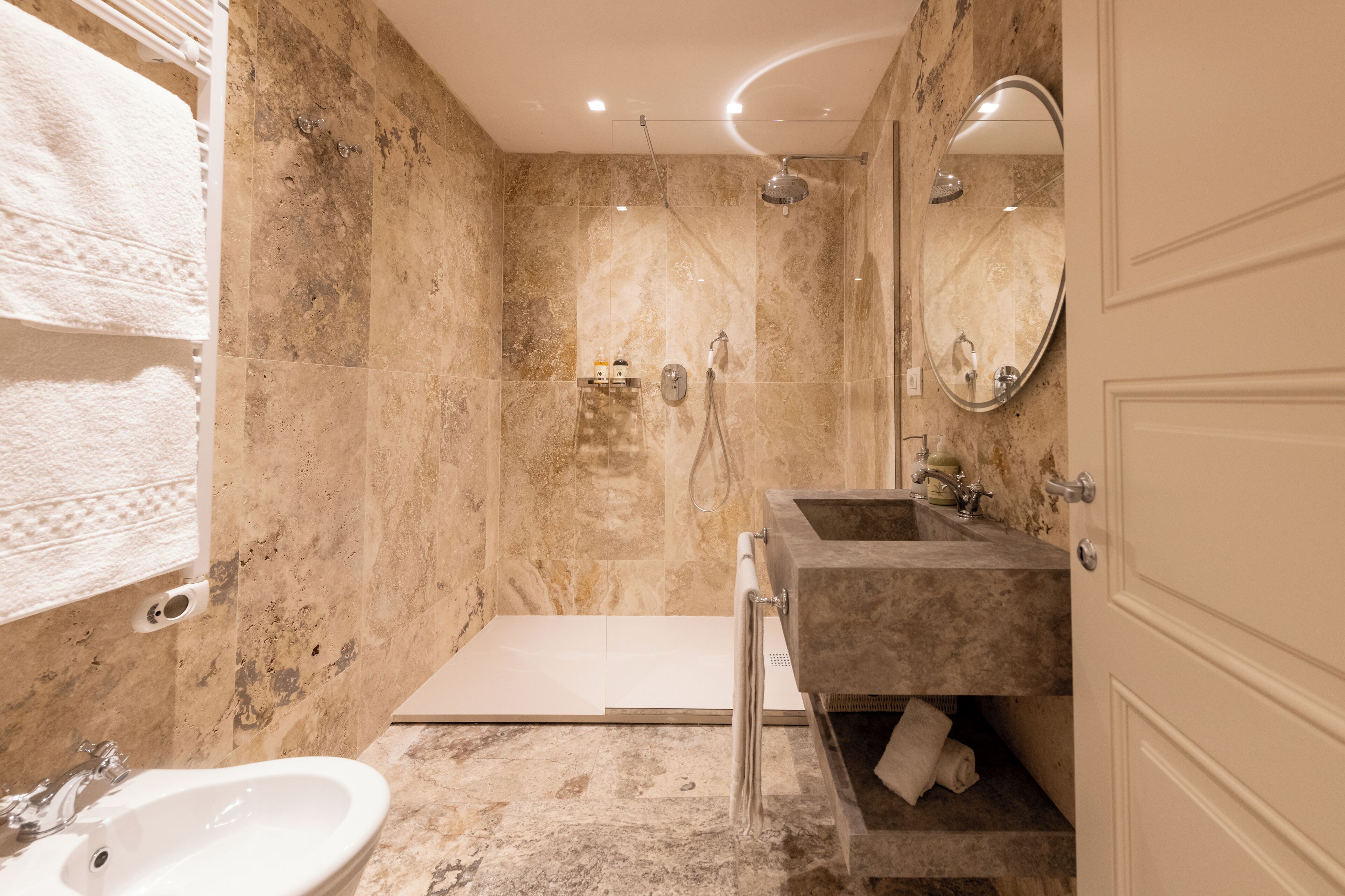 A modern bathroom with a marble shower, a sink, and a mirror.