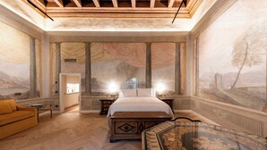 A spacious bedroom with a large bed, a wooden nightstand, a sofa, and a decorative mirror. - Palazzo Doni by Florence Art Apartments (Florence)