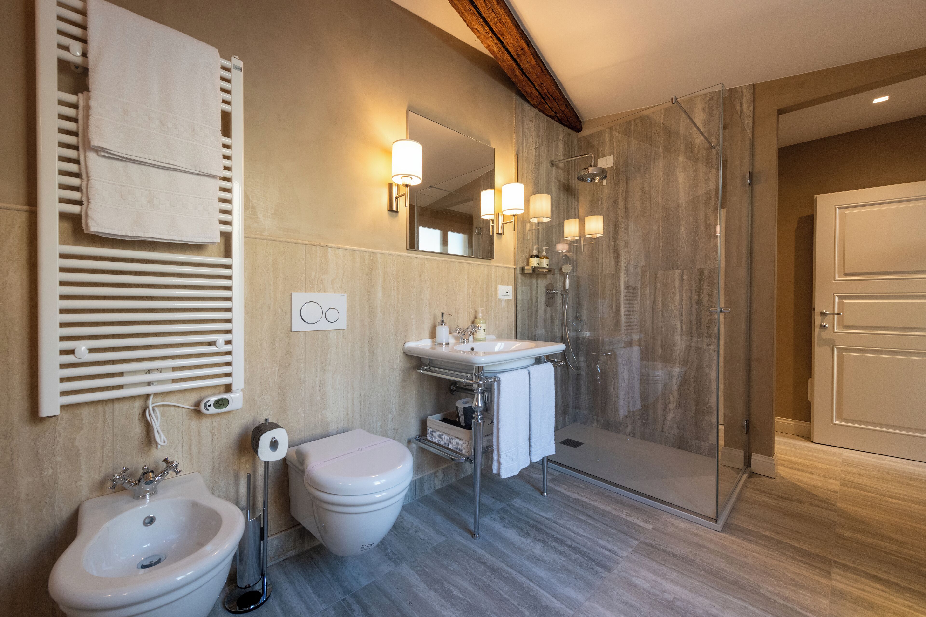 A modern bathroom with a bidet, sink, mirror, and glass shower enclosure.