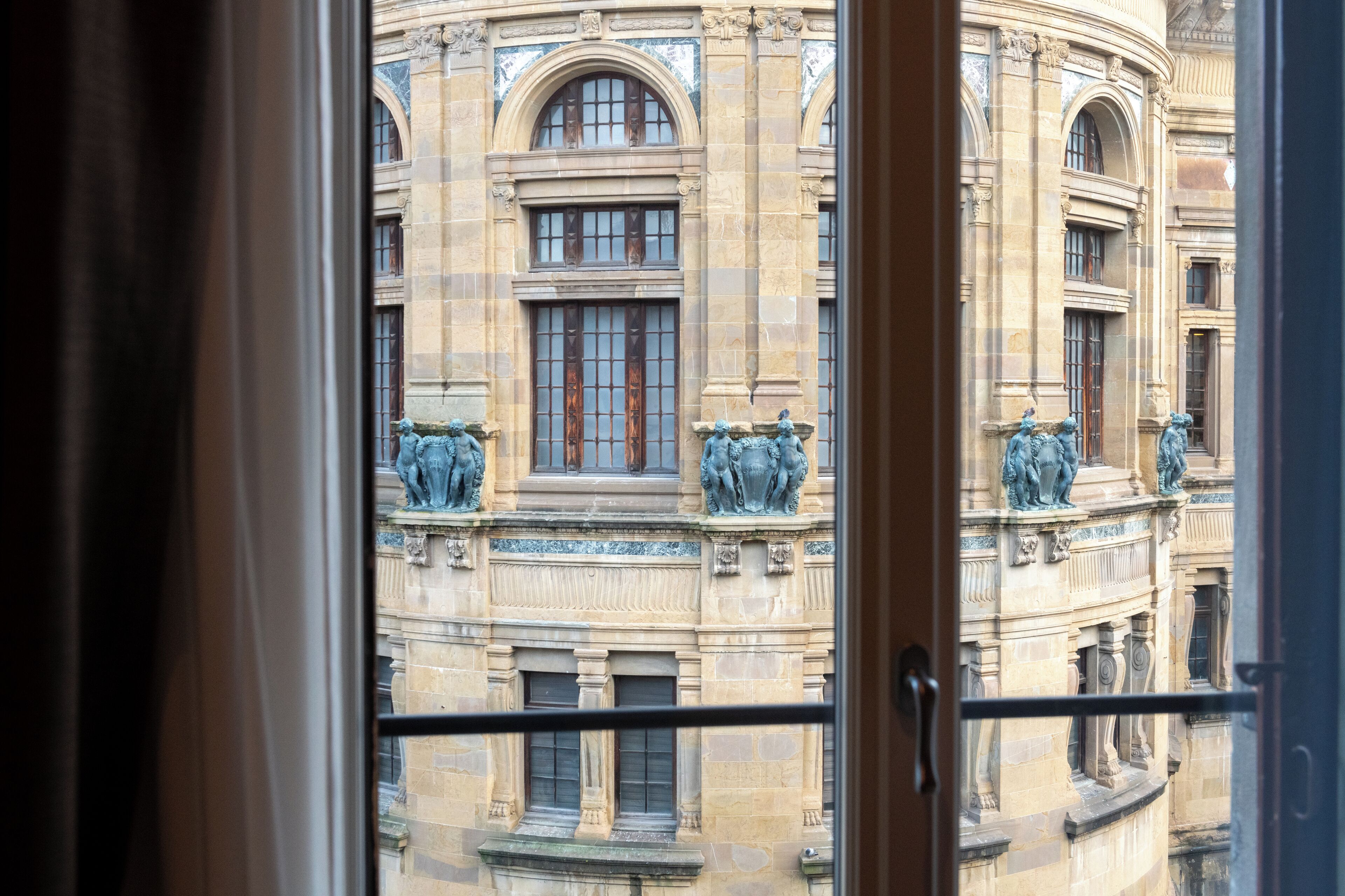 Vista de un edificio clásico con ventanas de arco y estatuas en el balcón.