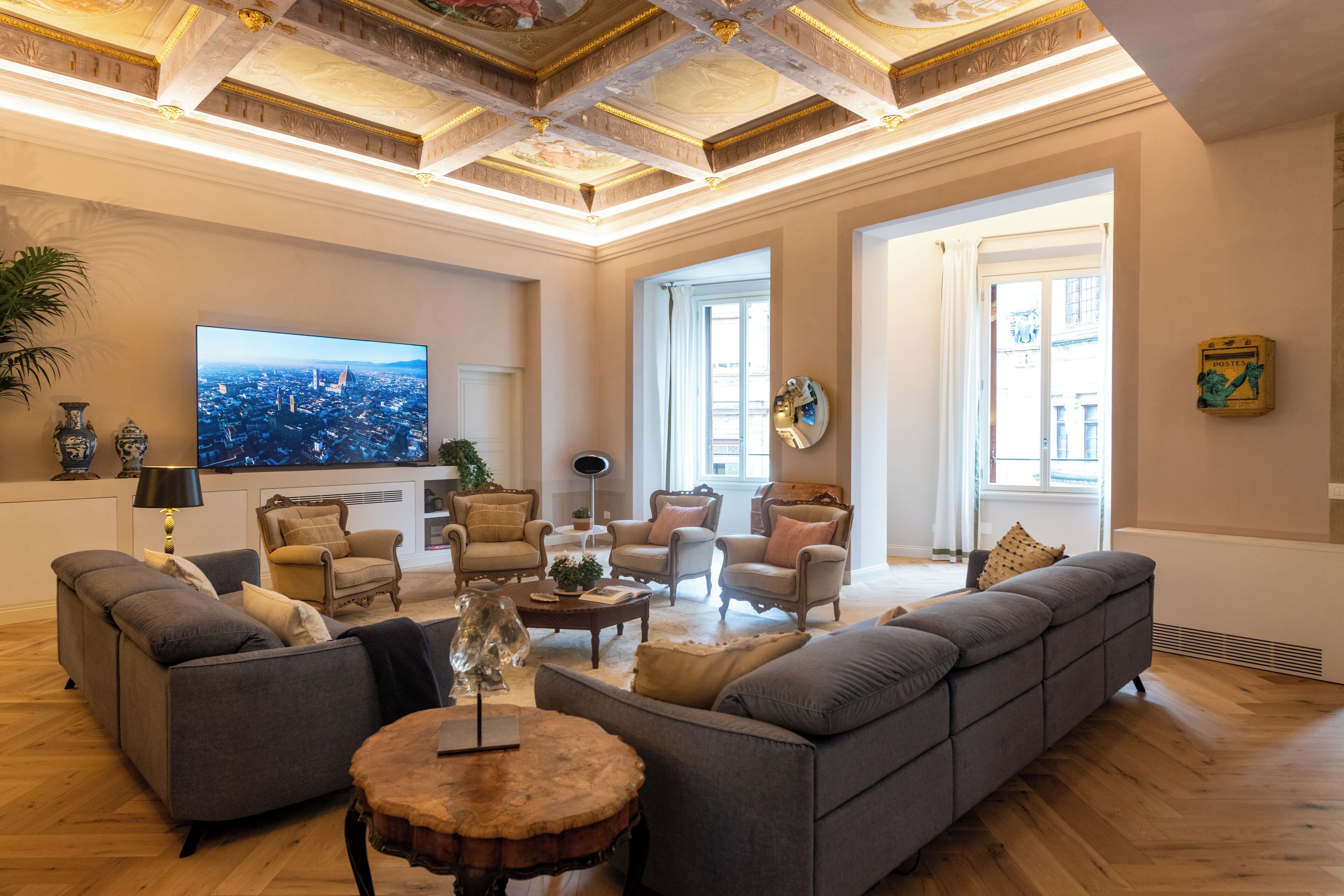 A spacious living room with a large flat-screen TV, multiple seating areas, and a wooden coffee table.