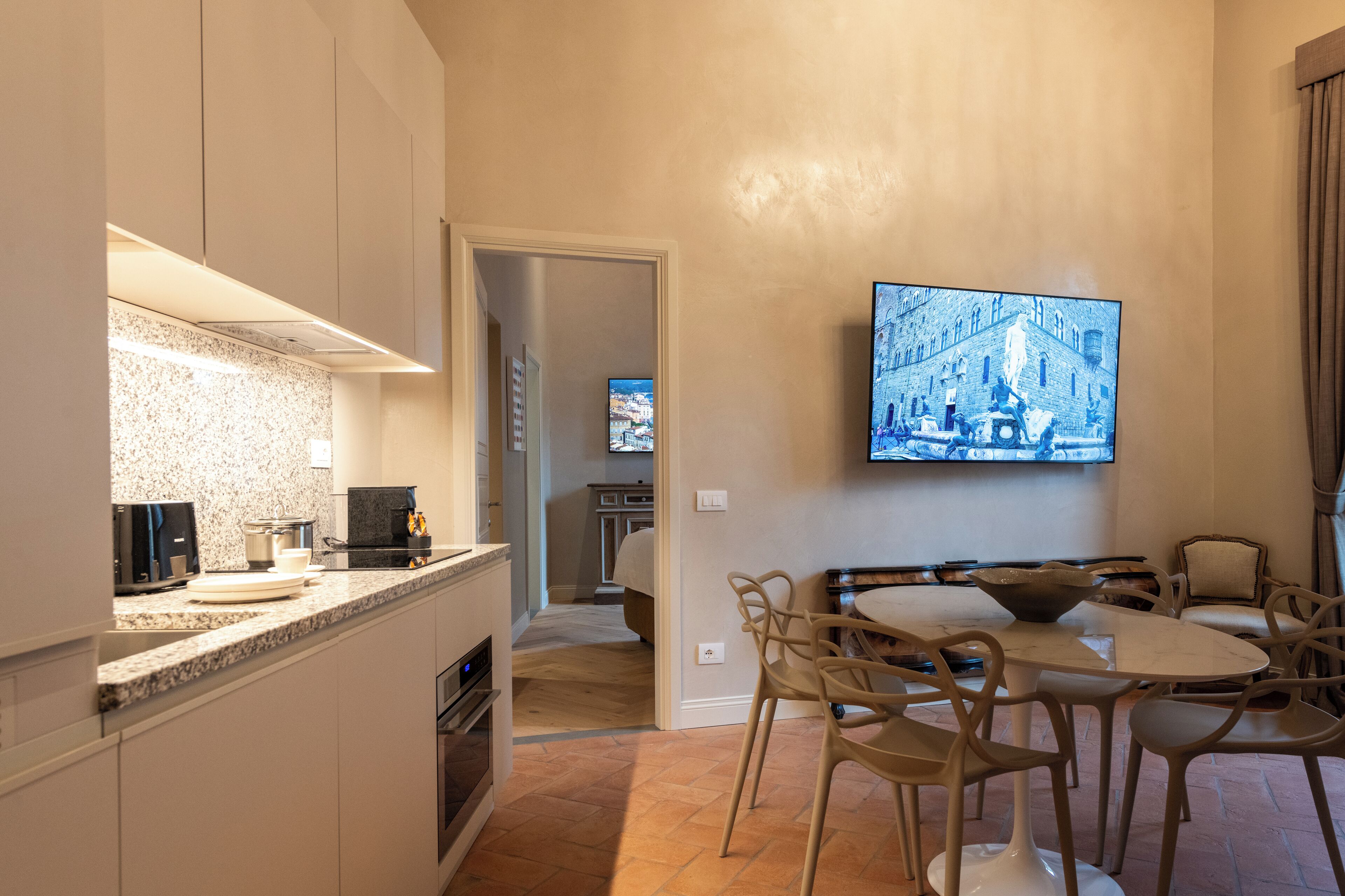 Una cocina moderna con encimeras de granito, horno empotrado y comedor con mesa y sillas.