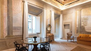 A spacious room with a large dining table, chairs, a sofa, and a fireplace. - Palazzo Doni by Florence Art Apartments (Florence)