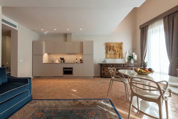 A modern kitchen with built-in appliances, a dining area with a table and chairs, and a sofa in a living area.
