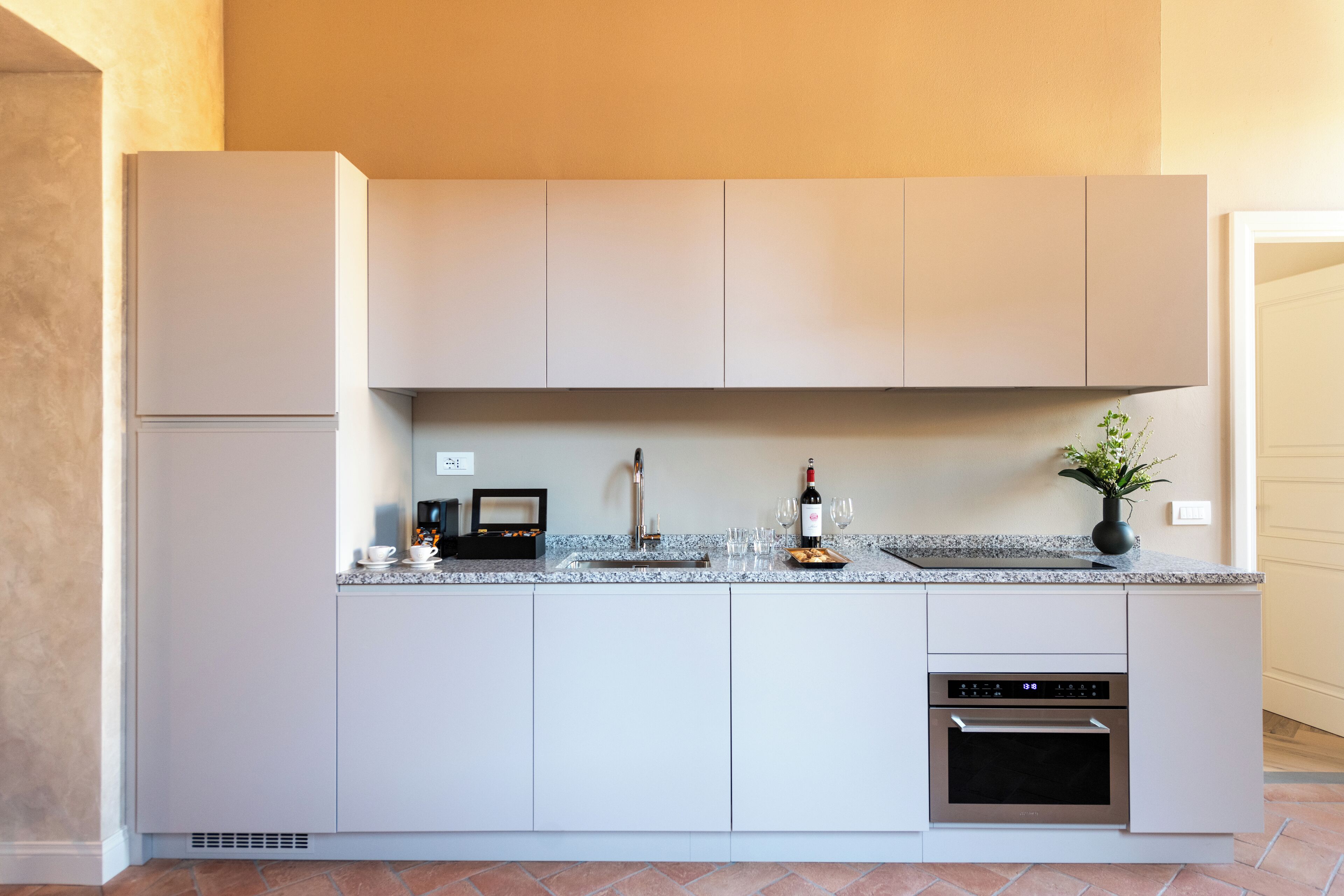 A modern kitchen with a built-in oven, a wine bottle, and a plant on the counter.