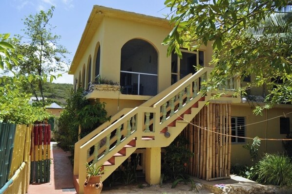 A yellow building with a staircase leading to a balcony.