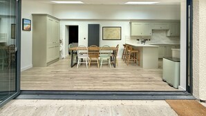 Cocina moderna con comedor, que incluye una mesa y sillas de madera, una isla de cocina y vistas a la habitación contigua.