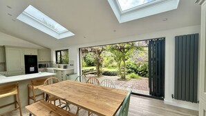 Una cocina moderna con una gran mesa de comedor, tragaluces y vistas a un jardín.