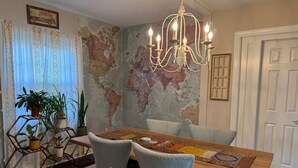 Un comedor con una mesa de madera, dos sillas, una araña y un mapa mundial en la pared.