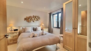 A modern bedroom with a large bed, bedside tables, a wardrobe, and a decorative wall piece. - Central Spacious Ground Floor Flat with Courtyard (Kingsbridge)
