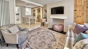 A living room with a sofa, a coffee table, a fireplace, and a TV mounted on the wall. - Farthing Cottage…cute ‘n’ cosy! (Kingsbridge)