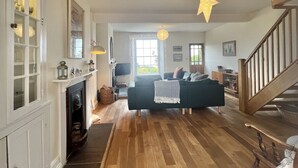A spacious living room with a fireplace, a sofa, and a staircase.
