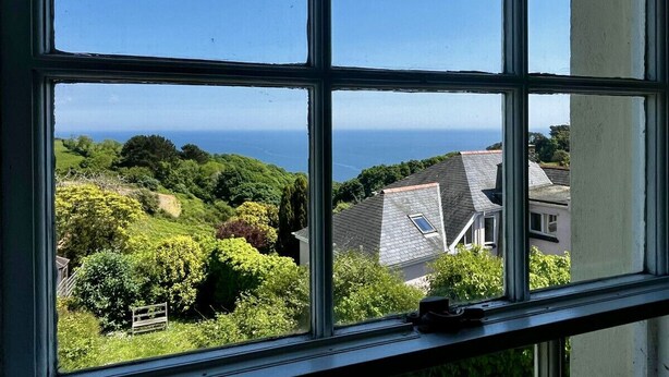 A window view of a coastal area with houses and greenery.