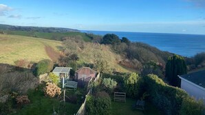 A coastal property with a large house, a small shed, and a garden.