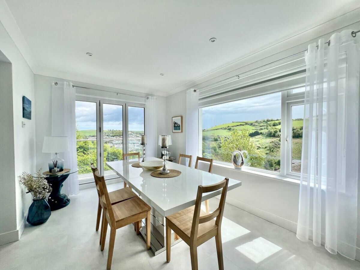 A dining area with a large table, chairs, and a view of the countryside.
