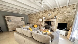 Un salon avec un mur en pierre, une cheminée, un canapé et un téléviseur.