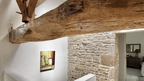 Un intérieur rustique avec des poutres apparentes, un mur en pierre et un tableau encadré accroché au mur.