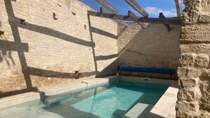 Une piscine avec des murs en pierre et une structure de plafond en bois.