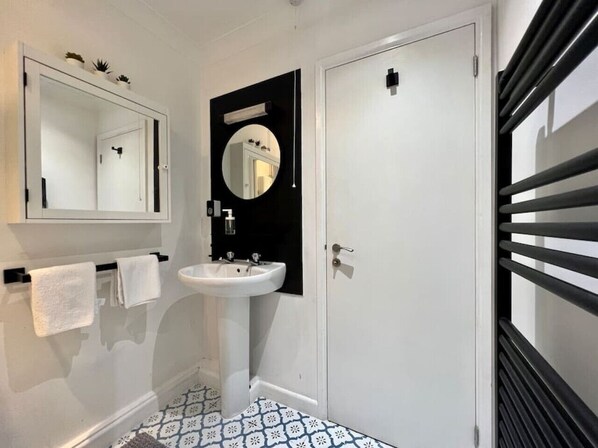 Un baño con un lavabo blanco, un espejo y una puerta con marco negro.