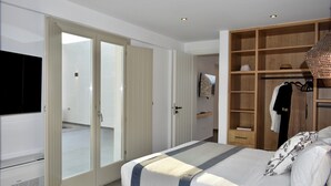 A modern bedroom with a large bed, a wardrobe, and a television.