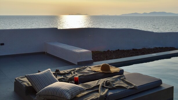 A rooftop terrace with a view of the sea, a sofa, and a small pool.