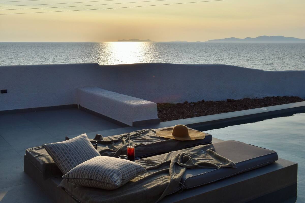 A rooftop terrace with a view of the sea, a sofa, and a small pool.