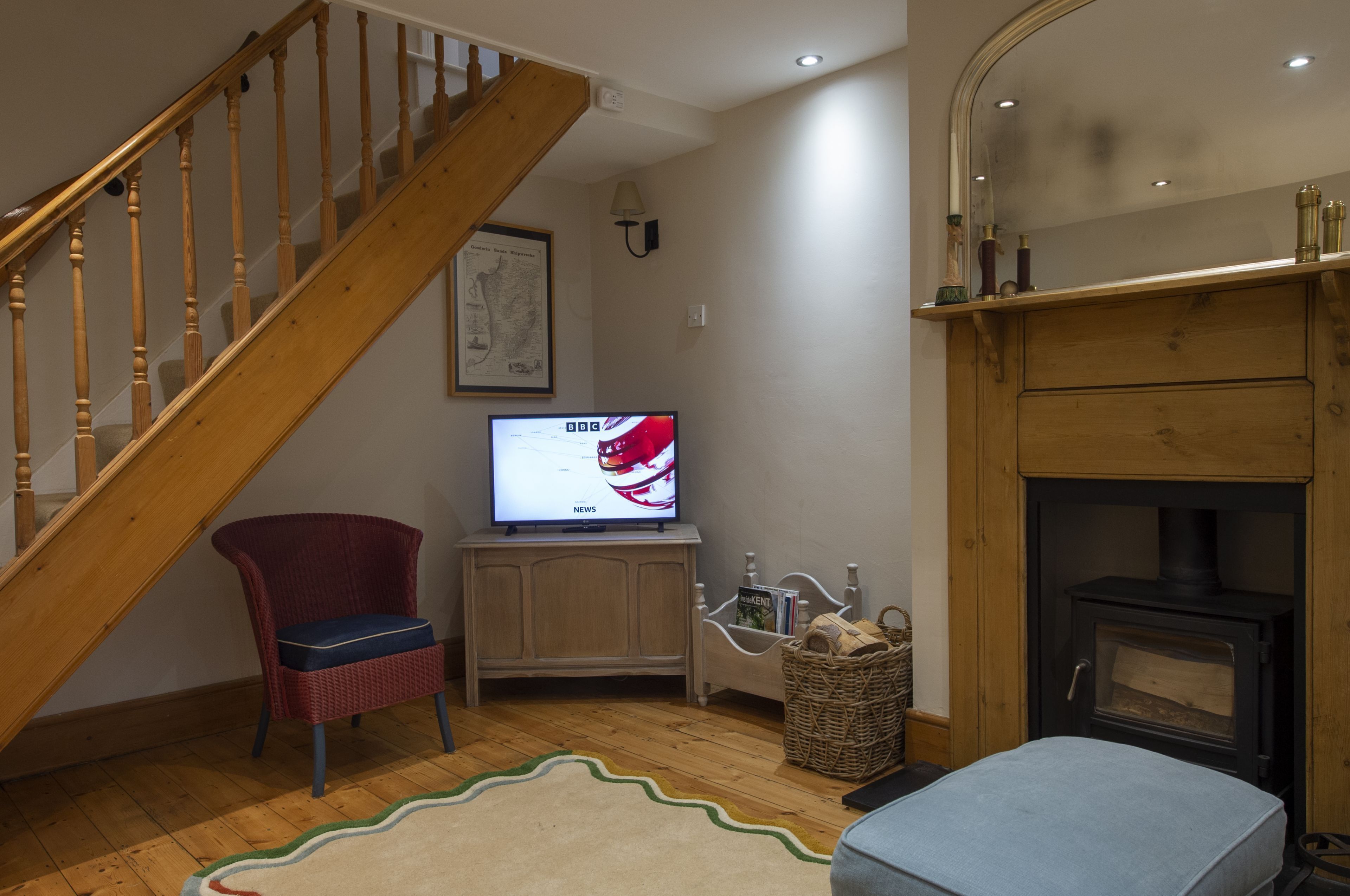 A living room with a wooden staircase, a television, a fireplace, and a wicker basket.