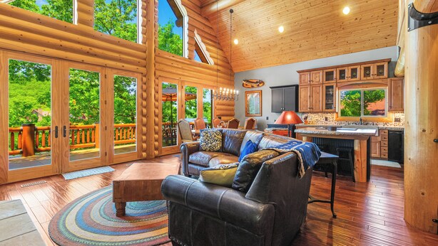 A spacious living room with a large sofa, a dining area, and a kitchen with wooden cabinets.