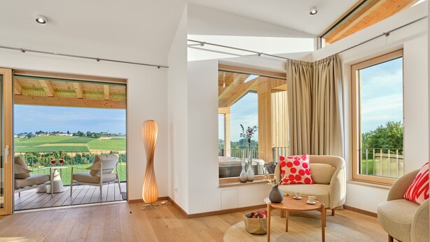 A spacious room with a large window, a balcony, and a cozy seating area. - Anetseder Landhotel & Lofts (Thyrnau)