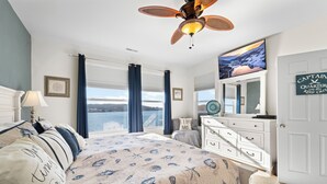 Una camera da letto con un letto, una ventola a soffitto, un comò e una televisione.