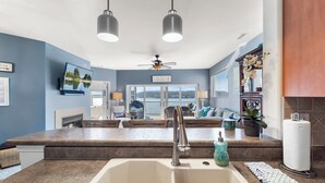 Una cucina moderna con isola centrale, lavello incassato e illuminazione a sospensione.